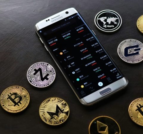 pexels-photo-11279906-11279906 A collection of cryptocurrency coins and a smartphone displaying a digital trading platform.